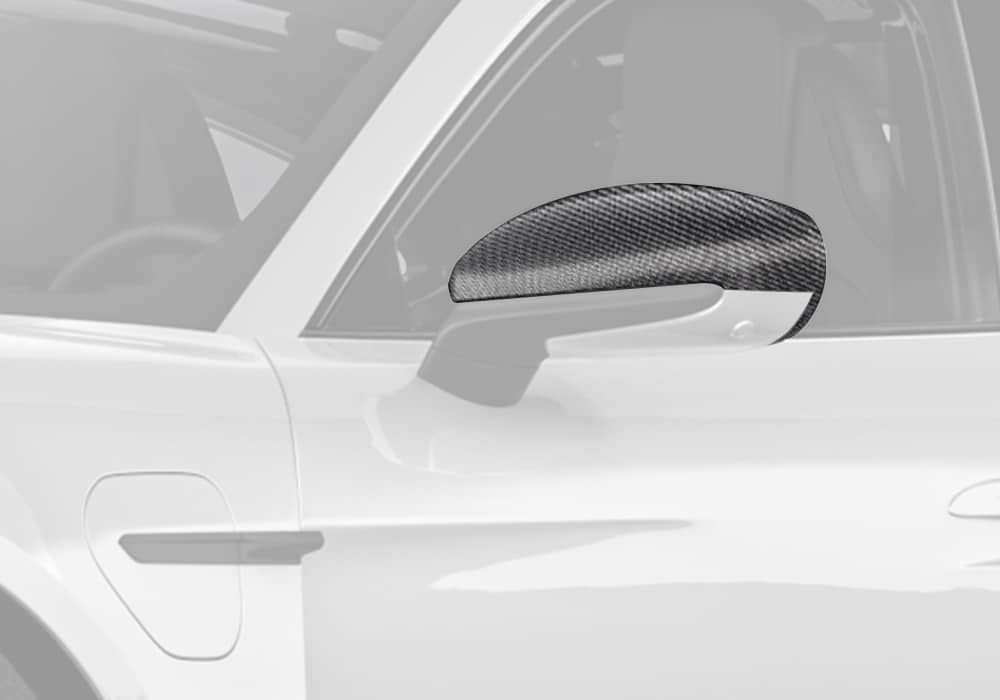 A Porsche Taycan with high-gloss carbon fiber mirror covers, showcasing the seamless blend into the vehicle’s aerodynamics and design