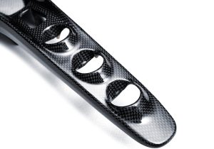Ferrari F8 Carbon Fiber Center Console Bridge reflecting light under natural sunlight, showcasing its glossy finish